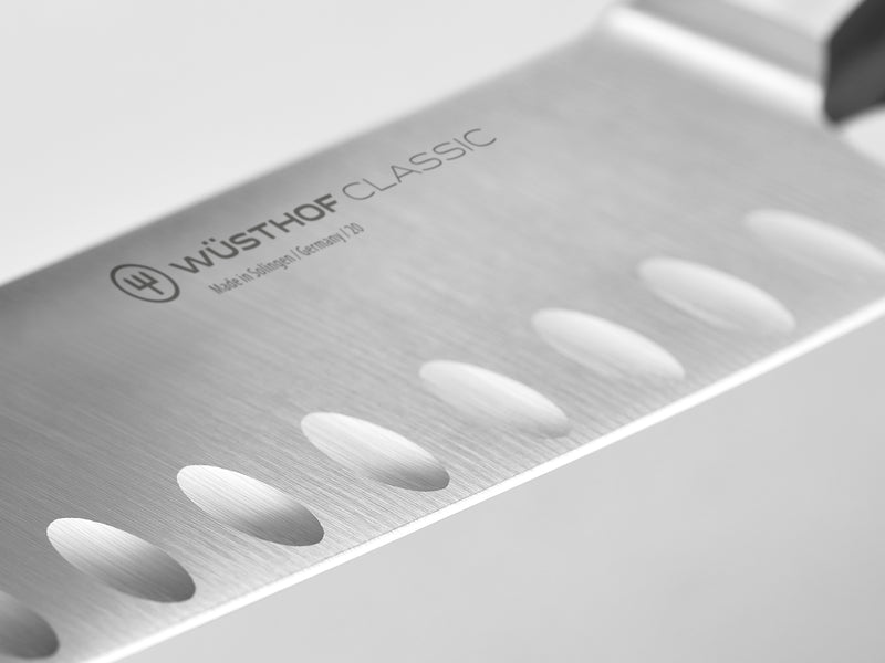 Classic 36-Piece Knife Block Set featuring a close-up of a forged German knife blade with hollow edges and etched WÜSTHOF CLASSIC logo for precise cutting.