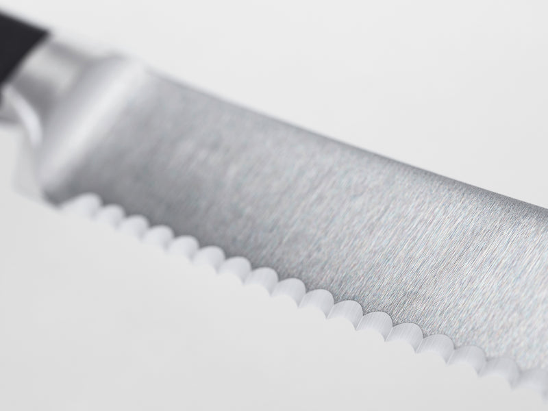 Classic 36-Piece Knife Block Set close-up of a serrated forged German blade with brushed finish and black ergonomic handle for precise slicing.