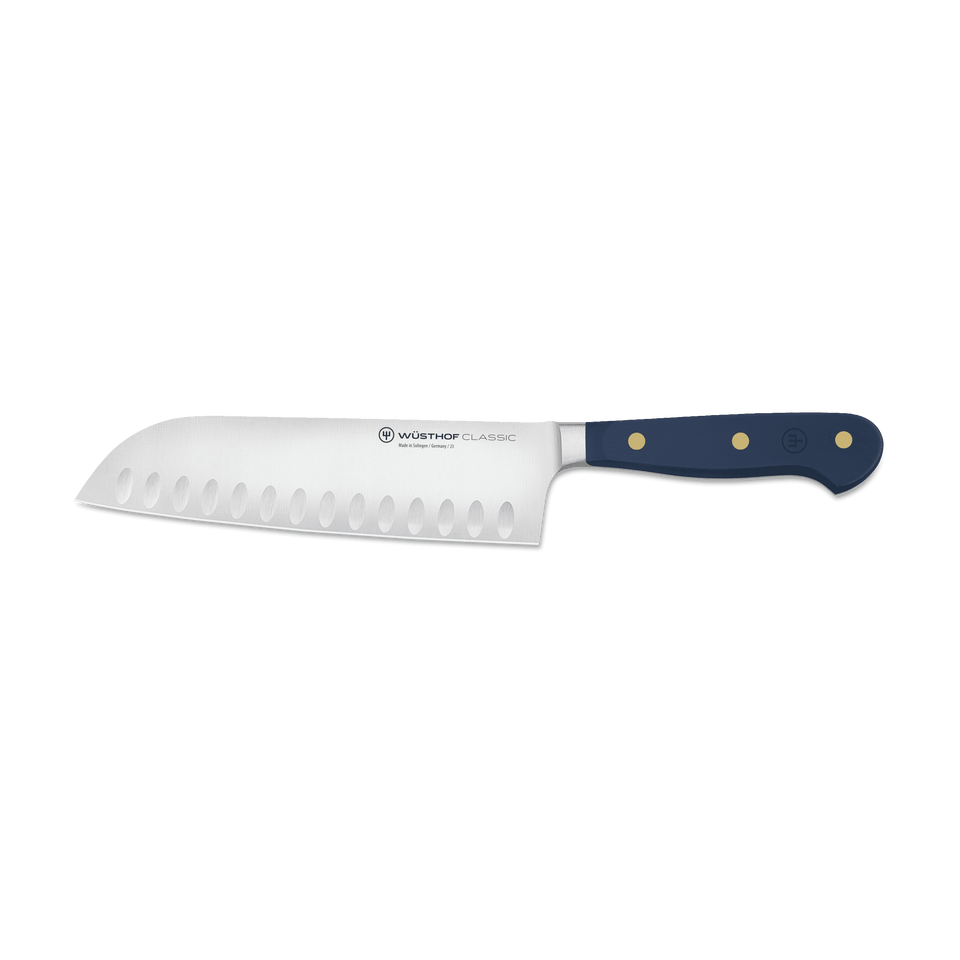 Classic 7" Hollow Edge Santoku with a polished forged German steel blade featuring scalloped indentations and a navy ergonomic handle with brass rivets for balanced control.