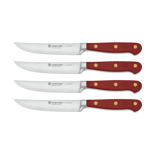 Classic 4-Piece Steak Knife Set featuring sharp curved stainless steel blades with full tang construction and deep red handles secured by three brass rivets.