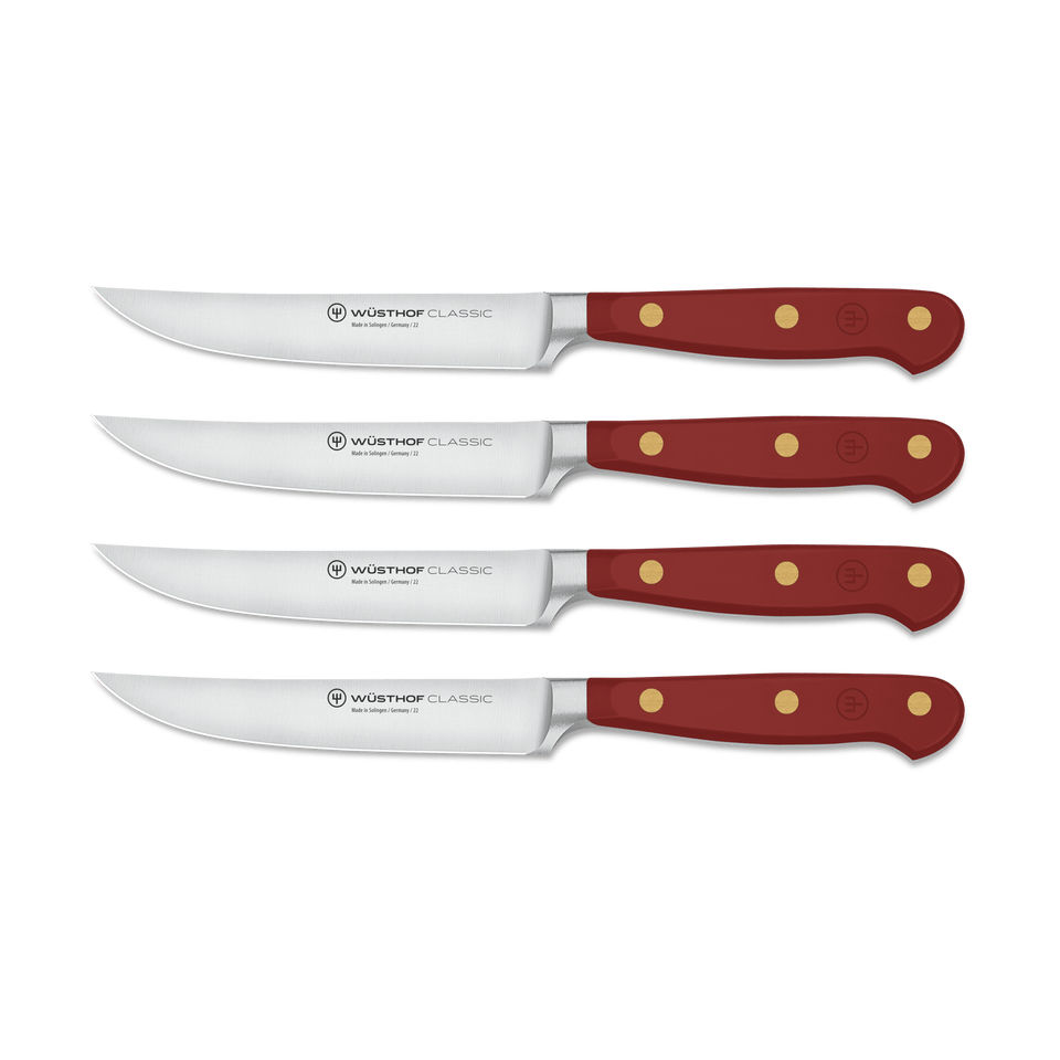Classic 4-Piece Steak Knife Set featuring sharp curved stainless steel blades with full tang construction and deep red handles secured by three brass rivets.
