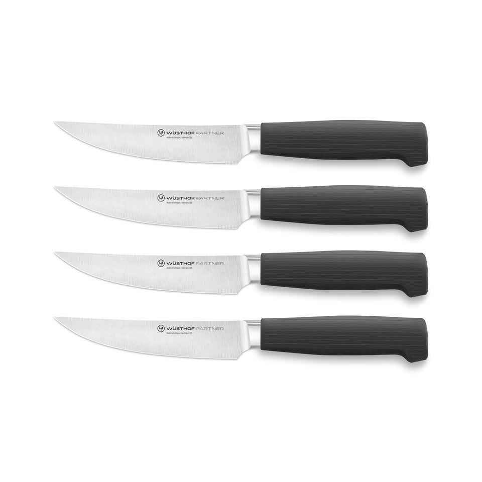 Partner 4-Piece Steak Knife Set with sharp forged German blades and textured black ergonomic handles for comfortable, precise cutting of steak and meats.