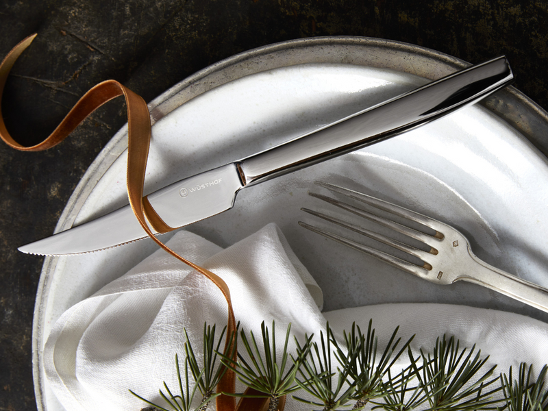 8-Piece Stainless Mignon Steak Knife Set featuring a polished stainless steel blade with a sleek mirror finish and ergonomic handle, displayed on a decorative plate.