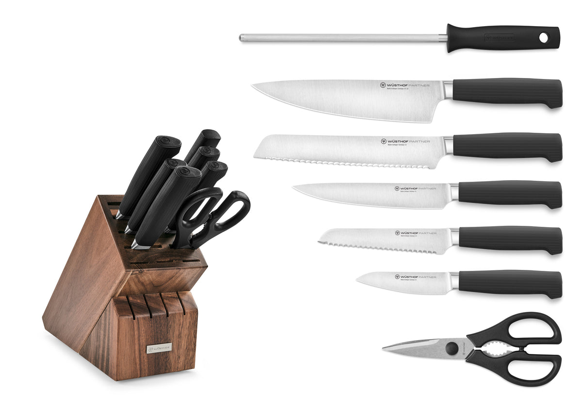 Partner 8-Piece Knife Block Set featuring forged German knives with black ergonomic handles, sharpening steel, kitchen scissors, and a walnut wood block.