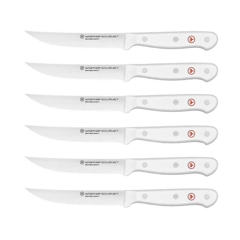 Gourmet White 18-Piece Knife Block Set displaying six serrated steak knives with sharp forged German steel blades and ergonomic white handles with rivet details and red emblem.
