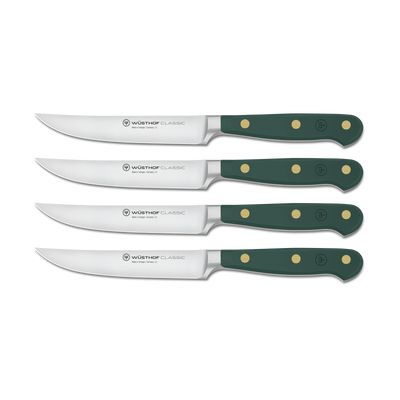 Set of four Wusthof Classic steak knives with green handles on a white background