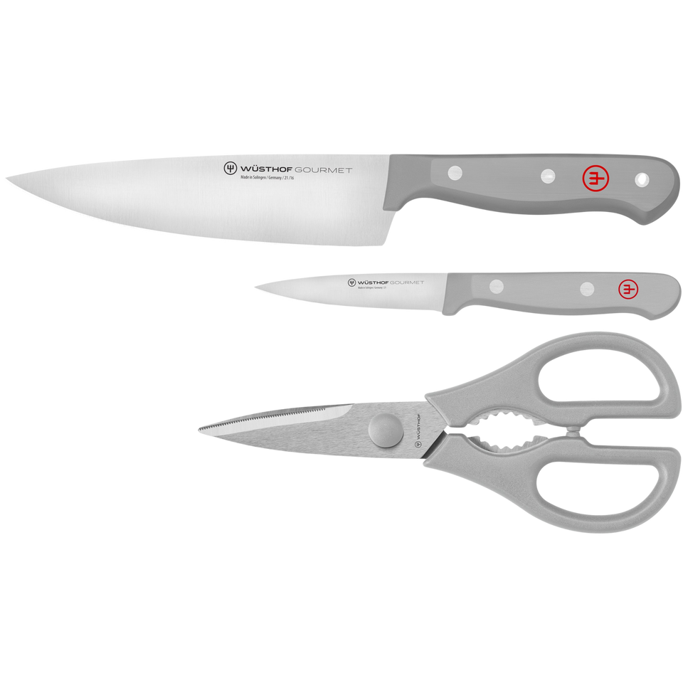 WÜSTHOF forged German knives with grey ergonomic handles and kitchen shears arranged in the Gourmet Grey 3-Piece Essentials Set.