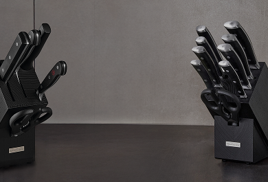 Set of black knives in a holder on a dark surface with a gray background