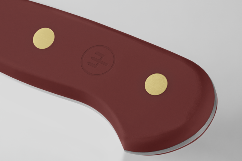 Close-up of the heel on the Classic 6" Utility Knife showing a burgundy ergonomic handle with two brass rivets and an embossed logo for dependable grip.