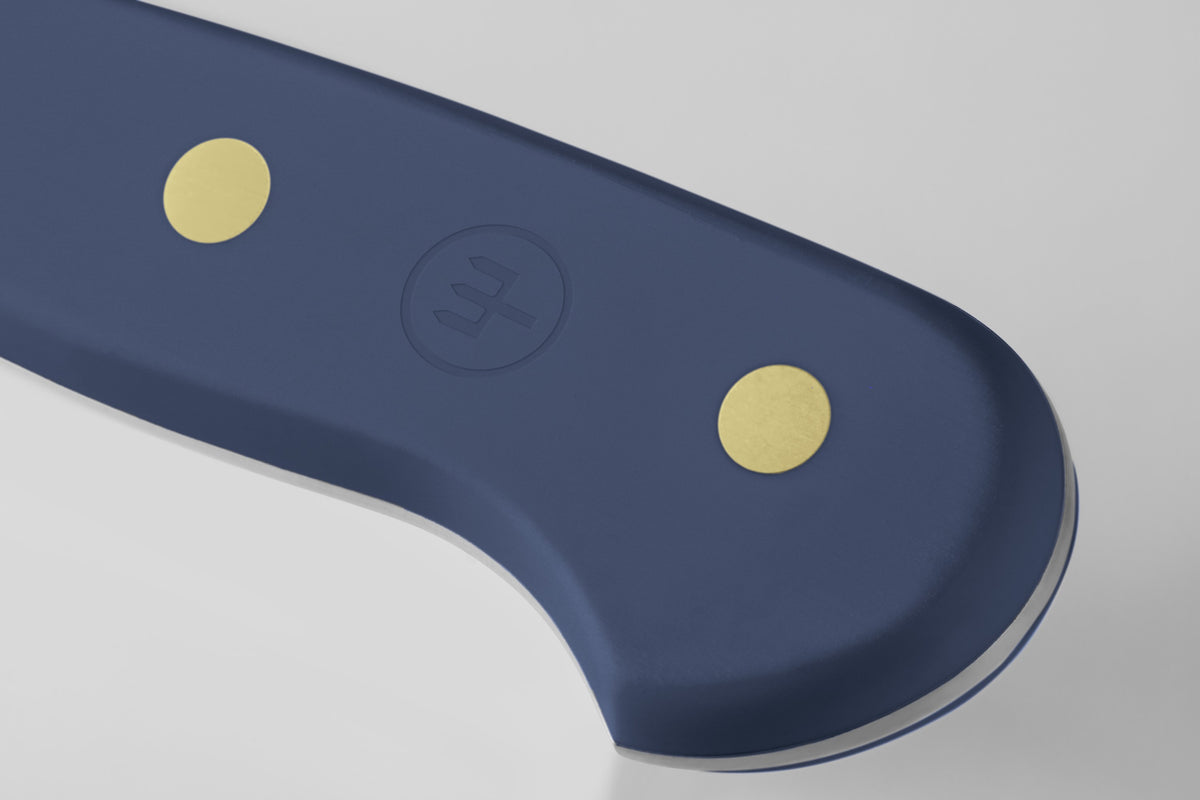Close-up of the heel of the Classic 6" Utility Knife featuring a navy ergonomic handle with two brass rivets and a subtle embossed logo for secure grip.