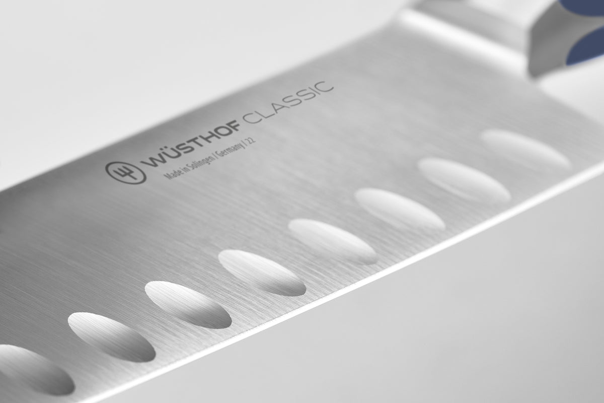 Close-up of the forged German steel blade with hollow scalloped edges on the Classic 7" Hollow Edge Santoku for reduced food sticking and precise slicing.