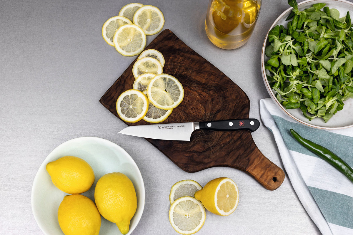 Classic 2-Piece Asian Knife Set featuring a forged German kitchen knife with a sharp stainless steel blade and black handle, slicing fresh lemons.