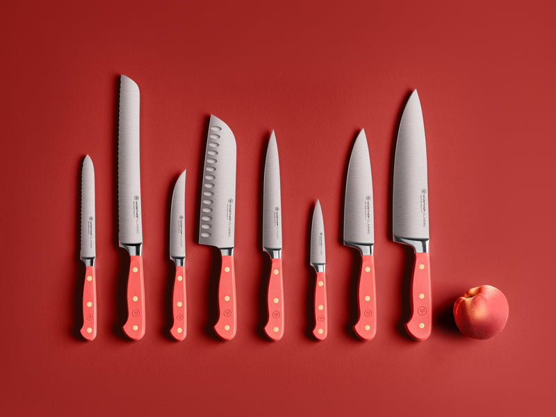 Classic 8" Chef's Knife displayed alongside a full set of matching knives with coral handles on a red background with a peach nearby