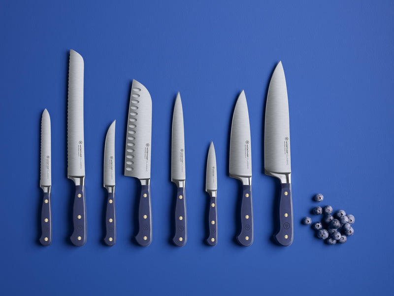 Classic 8-Piece Designer Knife Block Set displayed with forged German steel blades and dark ergonomic handles featuring brass rivets against a blue background.