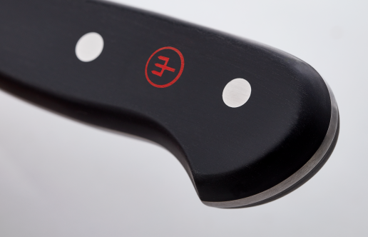 Close-up of the curved black handle heel with polished rivets and red logo on a forged German knife from the Classic 26-Piece Knife Block Set.