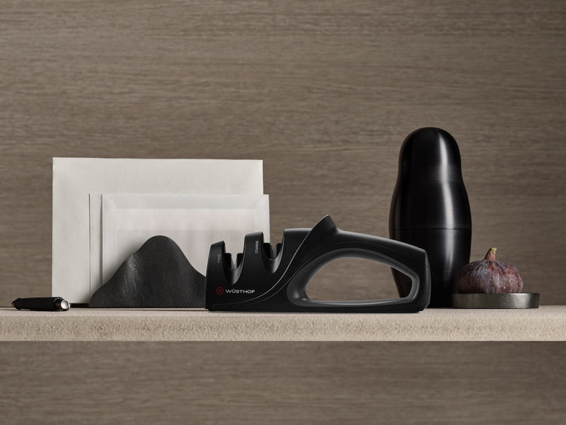Black desk organizer with stationery items on a wooden surface