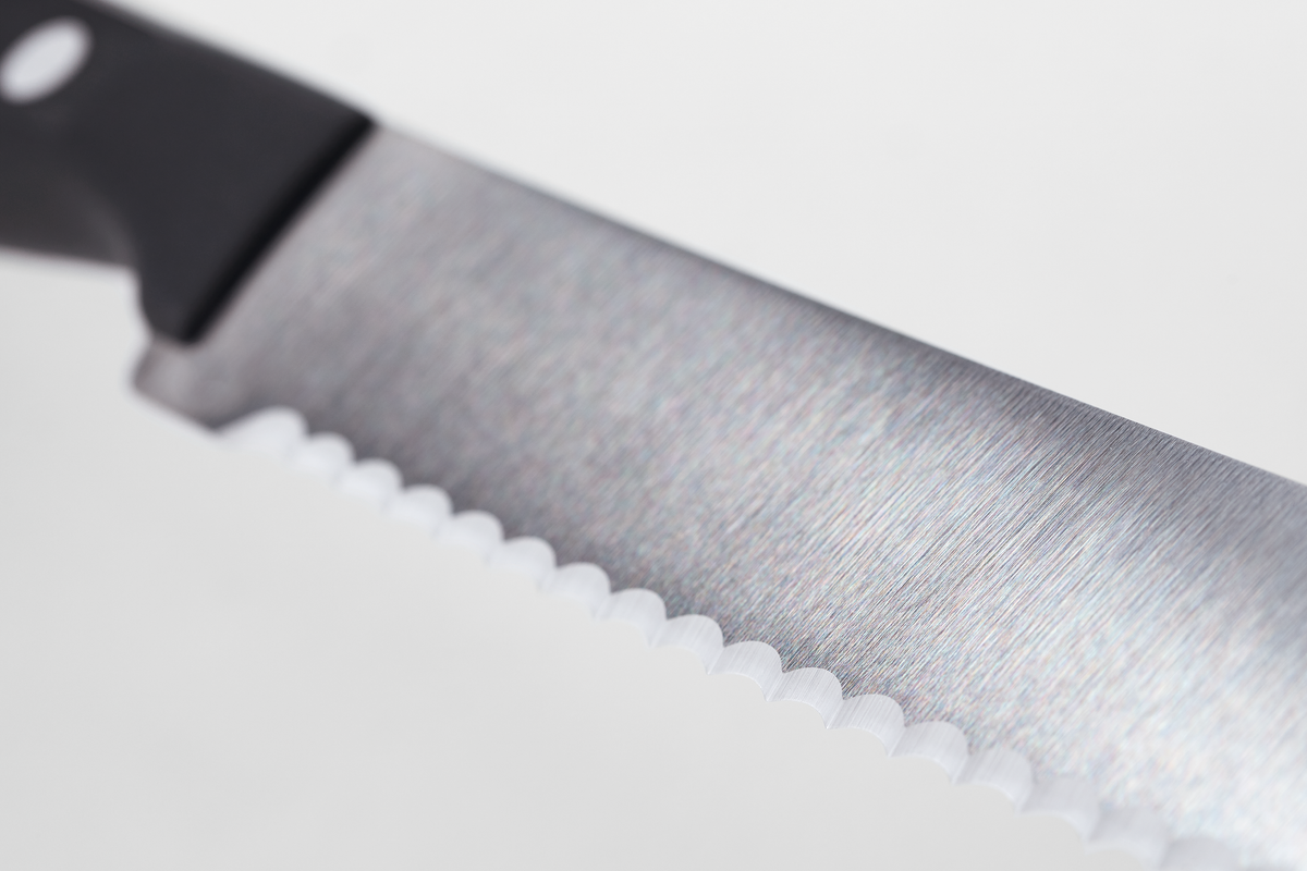Gourmet 18-Piece Knife Block Set close-up of a serrated forged German blade with brushed finish and a black ergonomic handle for precise cutting.