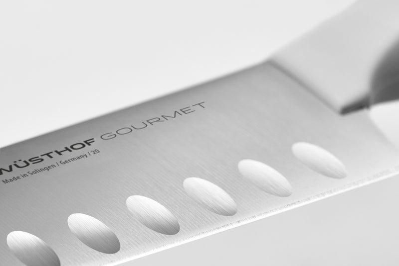 Close-up of a forged German blade with hollow edge indentations and a smooth ergonomic white handle from the Gourmet 16-Piece Knife Block Set.
