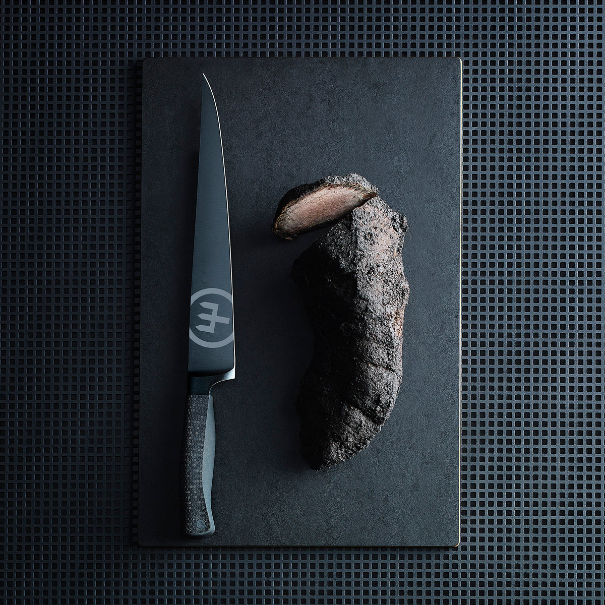 Performer 10" Carver with a sleek black forged German steel blade and textured ergonomic handle shown next to sliced roasted meat on a dark cutting board.