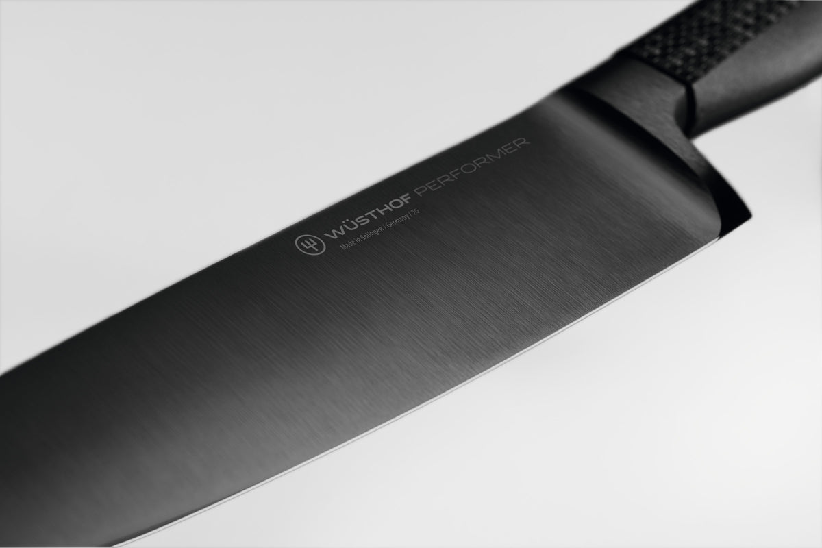 Performer 6" Chef's Knife featuring a finely forged black German steel blade with subtle branding and a textured handle for superior control.