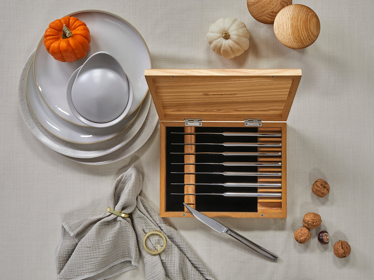 8-Piece Stainless Mignon Steak Knife Set with polished stainless steel blades and sleek handles, stored in a natural wood box, styled with autumn decor and tableware.