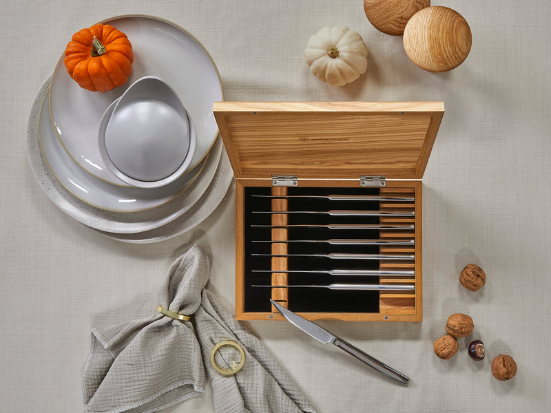 8-Piece Stainless Mignon Steak Knife Set with polished stainless steel blades and sleek handles, stored in a natural wood box, styled with autumn decor and tableware.