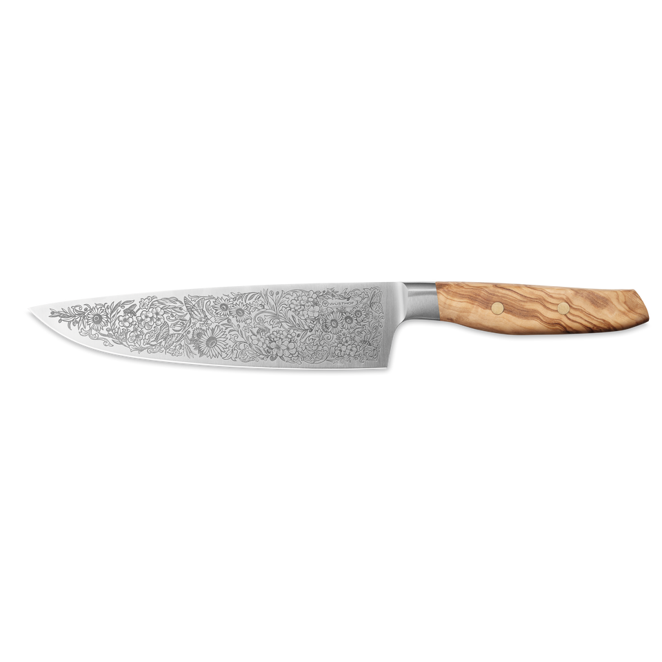 Amici 1814 chef’s knife featuring a detailed floral pattern engraved on the blade and a polished olive wood handle with brass rivets.