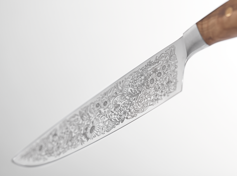 Amici 1814 forged kitchen knife with an elegantly detailed floral engraving covering the blade and a smooth wooden handle with brass rivets.