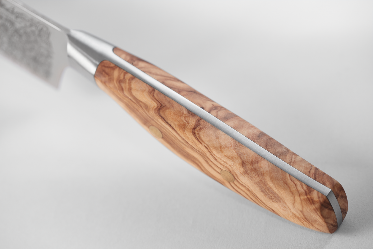 Amici 1814 knife handle made from richly textured olive wood with visible grain patterns and polished full tang metal for strength and balance.