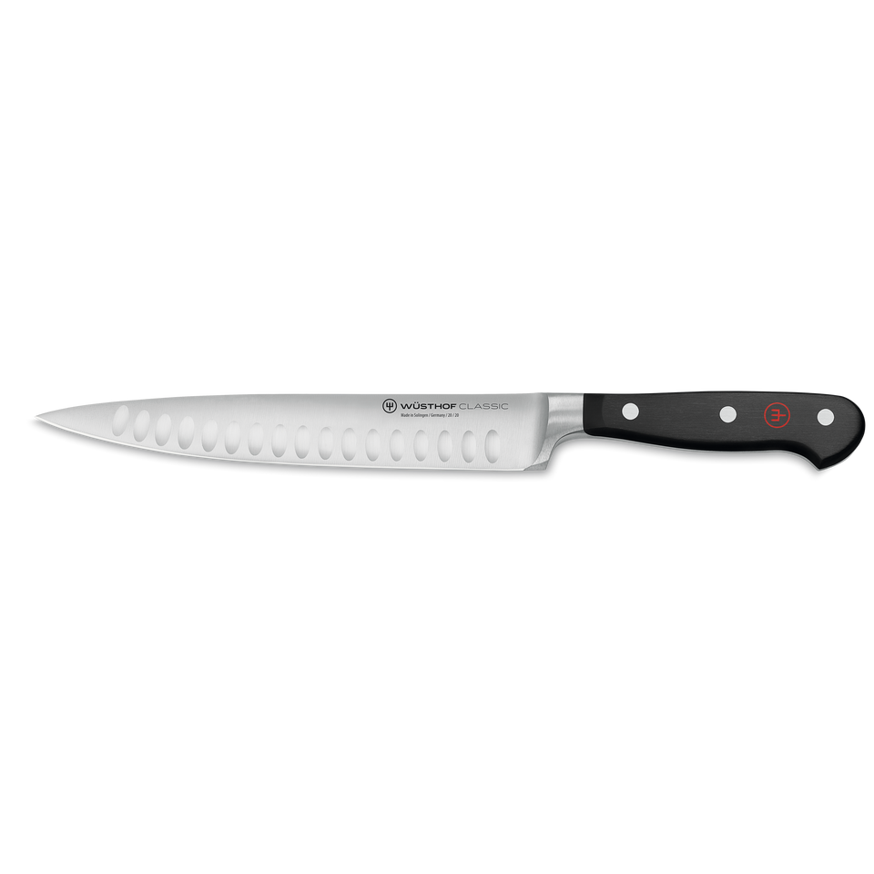 Classic 8" Hollow Edge Carving Knife with a sharply tapered, forged stainless steel blade featuring scalloped hollow edges and a black ergonomic handle with three rivets.