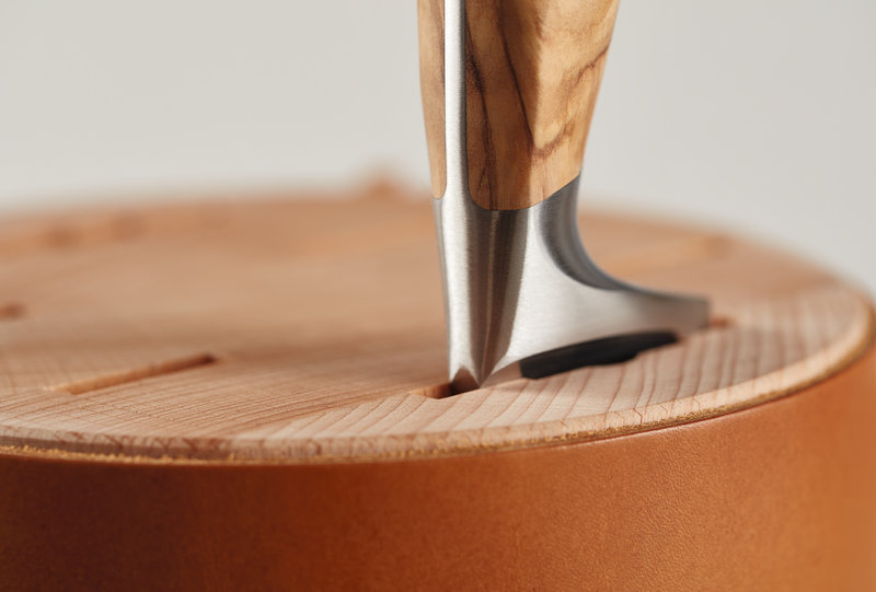 Villa 6-Slot Knife Block close-up showing a wooden-handled forged kitchen knife securely inserted in a smooth leather block with natural wood grain.