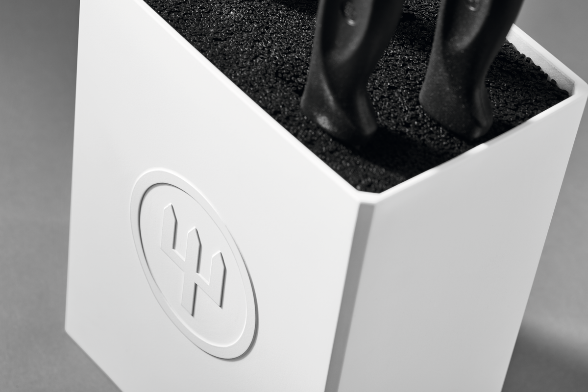 Create Knife Block close-up showing a white holder with textured black insert securing knife handles, featuring the embossed WÜSTHOF logo on the front.