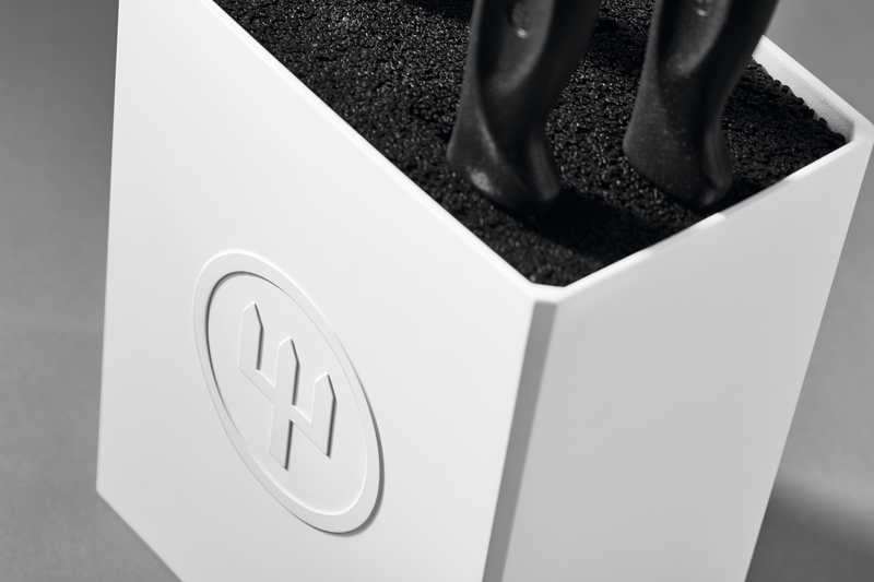 Create Knife Block close-up showing a white holder with textured black insert securing knife handles, featuring the embossed WÜSTHOF logo on the front.