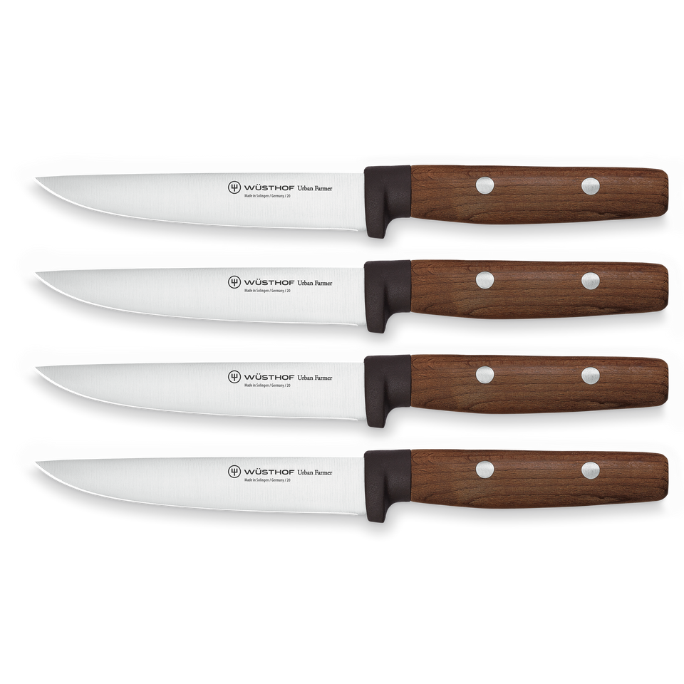 Four WÜSTHOF Urban Farmer 4-Piece Steak Knife Set knives with polished stainless steel blades and contoured wooden handles featuring three rivets.