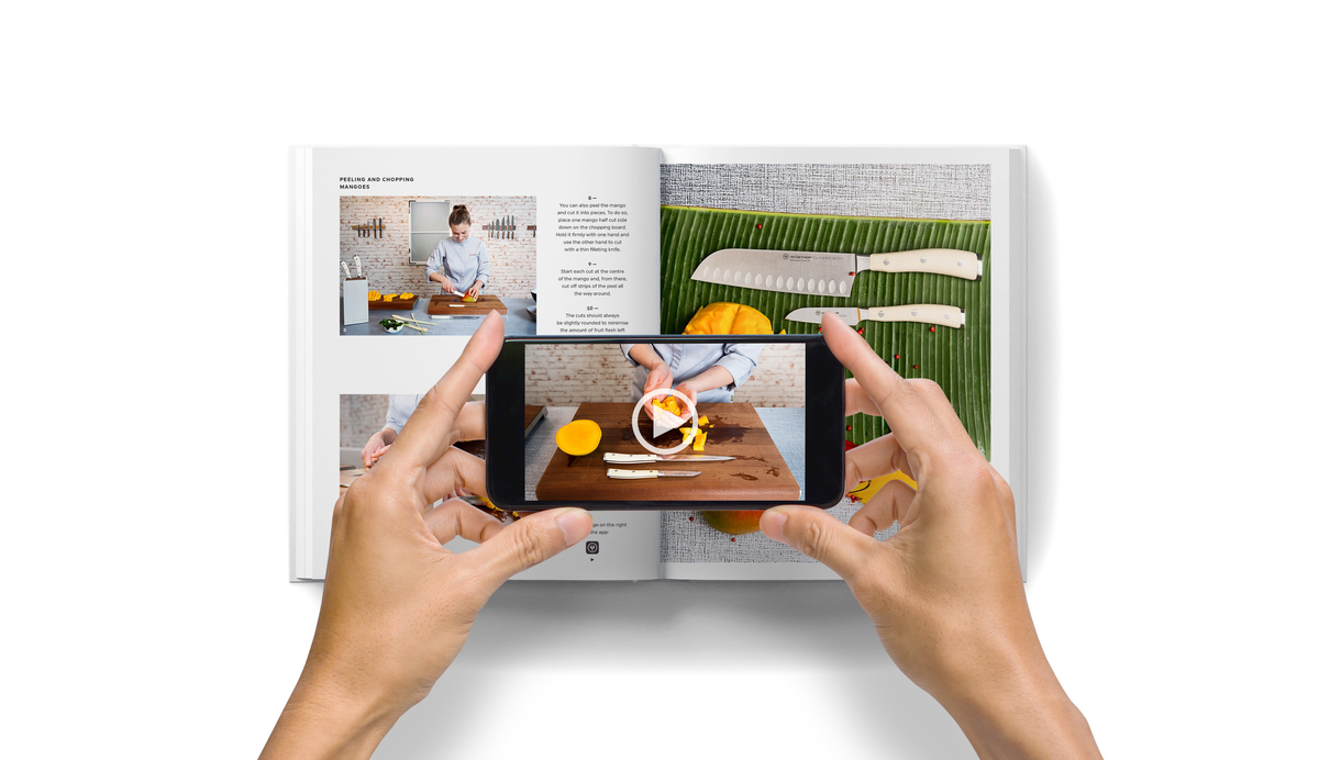 Hands holding a smartphone recording a cooking demonstration with WÜSTHOF knives and food on a wooden cutting board featured in Knives: Beyond Blades.