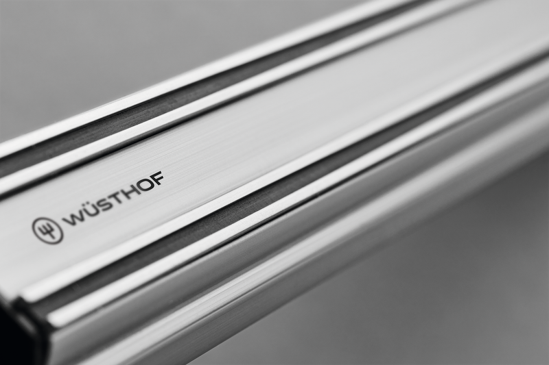 Close-up of the brushed stainless steel surface and engraved WÜSTHOF logo on the 12" Magnetic Holder for secure storage of forged kitchen knives.