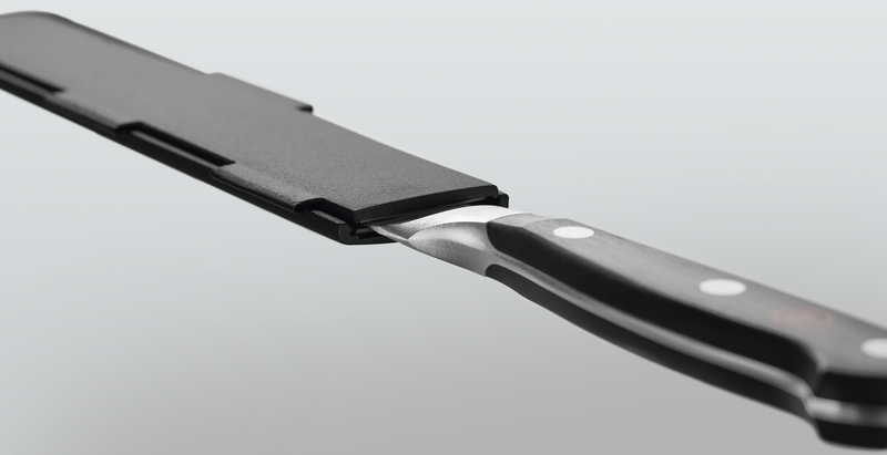 Narrow Magnetic Blade Guard in black securely enclosing the blade of a forged kitchen knife with a polished black handle and metal rivets for safe storage.