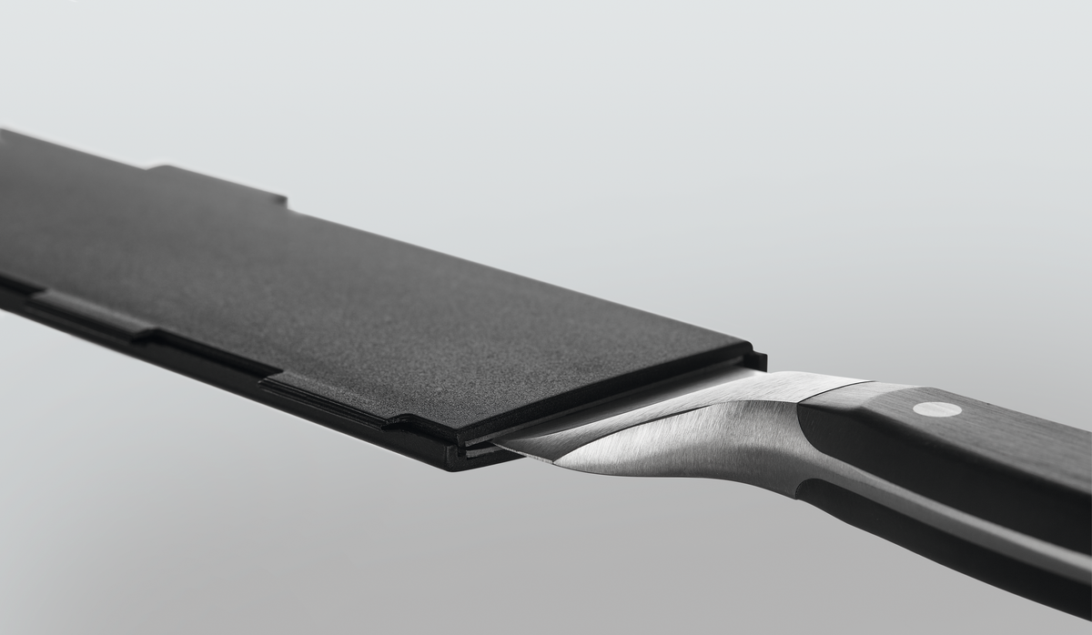 Wide Magnetic Blade Guard protecting the blade of a forged kitchen knife with a polished black handle and metal rivets for safe storage.