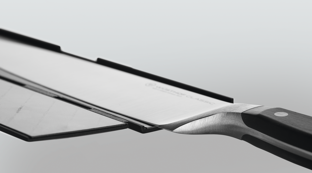 Wide Magnetic Blade Guard in black securely protecting the blade of a forged German kitchen knife with a polished handle and rivets for safe storage.