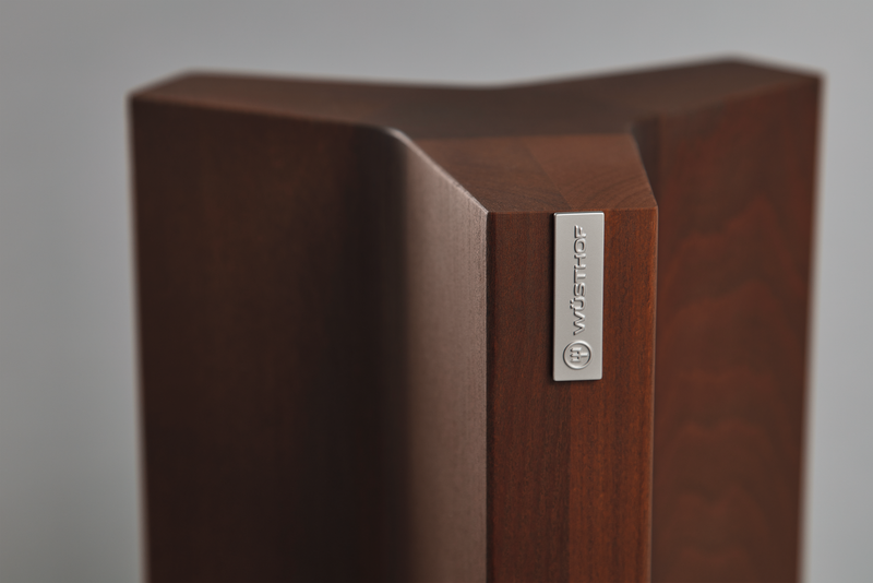 Close-up of a dark wood Magnetic Knife Block featuring a triangular shape and a metal WÜSTHOF logo plate for elegant kitchen knife storage.