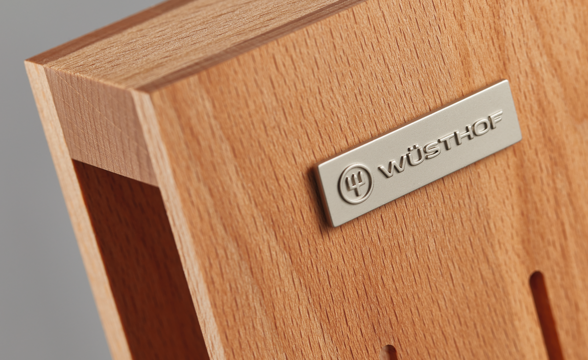 Close-up of the natural wood surface with a metal WÜSTHOF logo plate on the 7-Slot In-Drawer Knife Tray, highlighting its fine craftsmanship.