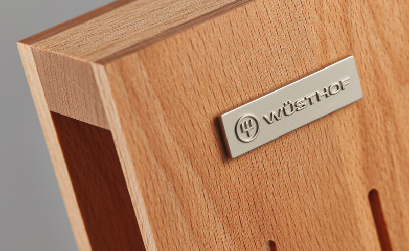 Close-up of the natural wood surface with a metal WÜSTHOF logo plate on the 7-Slot In-Drawer Knife Tray, highlighting its fine craftsmanship.