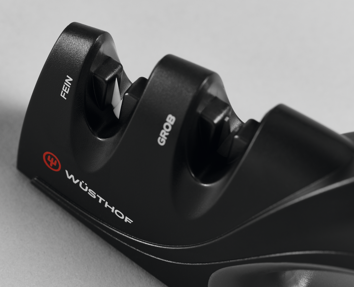 Two-Stage Hand-Held Knife Sharpener with black ergonomic body featuring coarse and fine sharpening slots for maintaining sharpness of WÜSTHOF forged kitchen knives.
