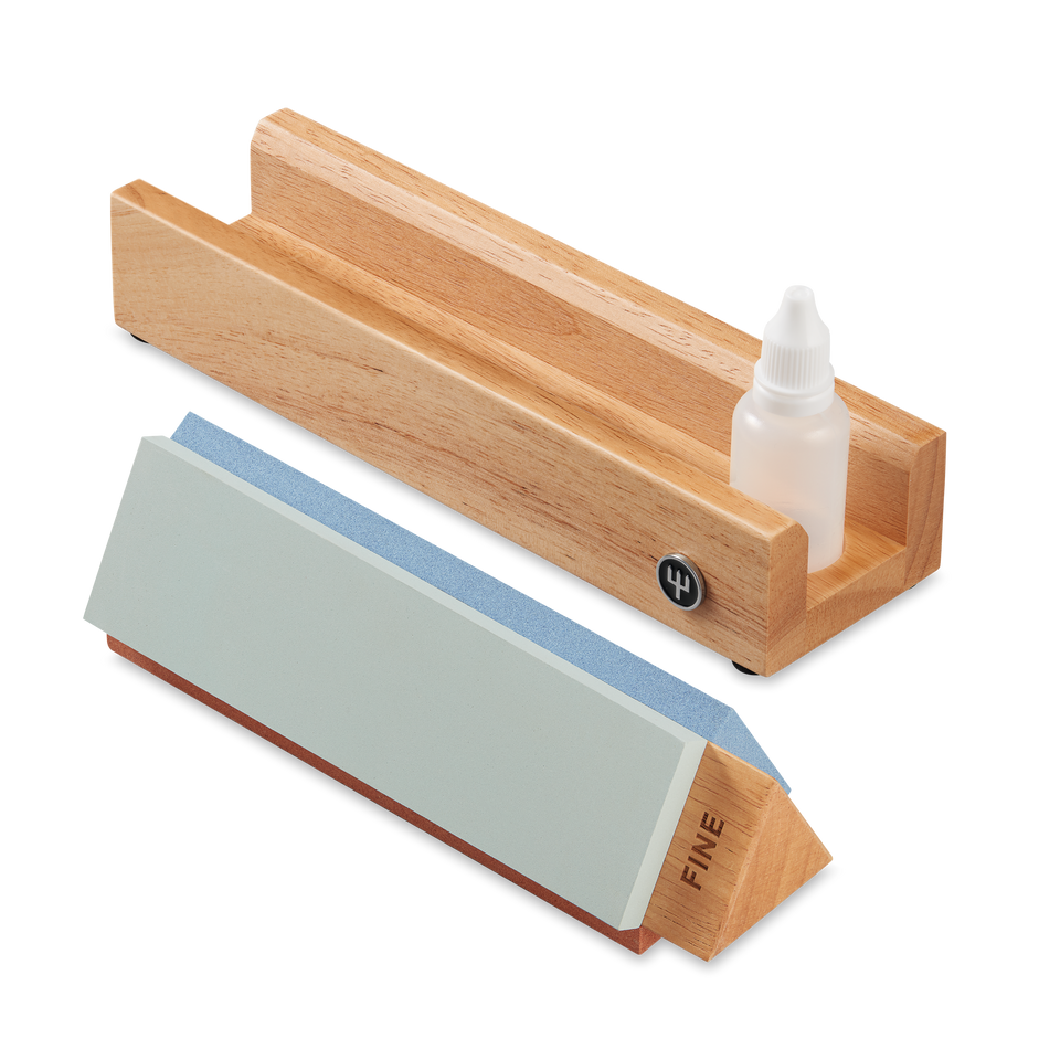 Tri-Stone Knife Sharpener featuring a wooden base with groove and sharpening stone with fine grit for restoring edge on forged kitchen knives.