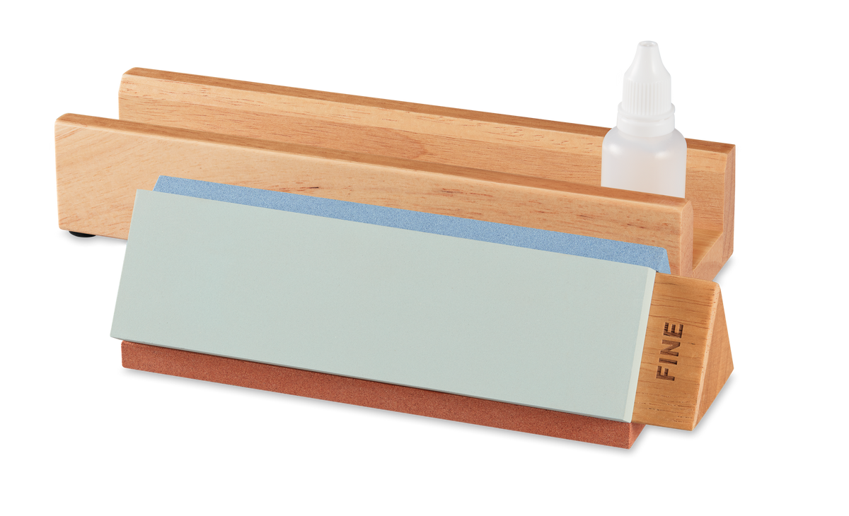 Tri-Stone Knife Sharpener featuring a wooden base with detachable fine and medium grit sharpening stones and a small bottle of honing oil for precise knife edge maintenance.