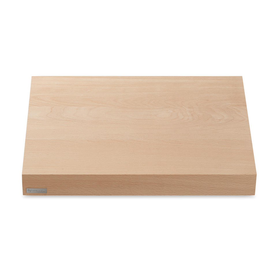 Beech Cutting Board made from smooth light wood with a thick rectangular design and a subtle natural grain, featuring a small metal logo plate.