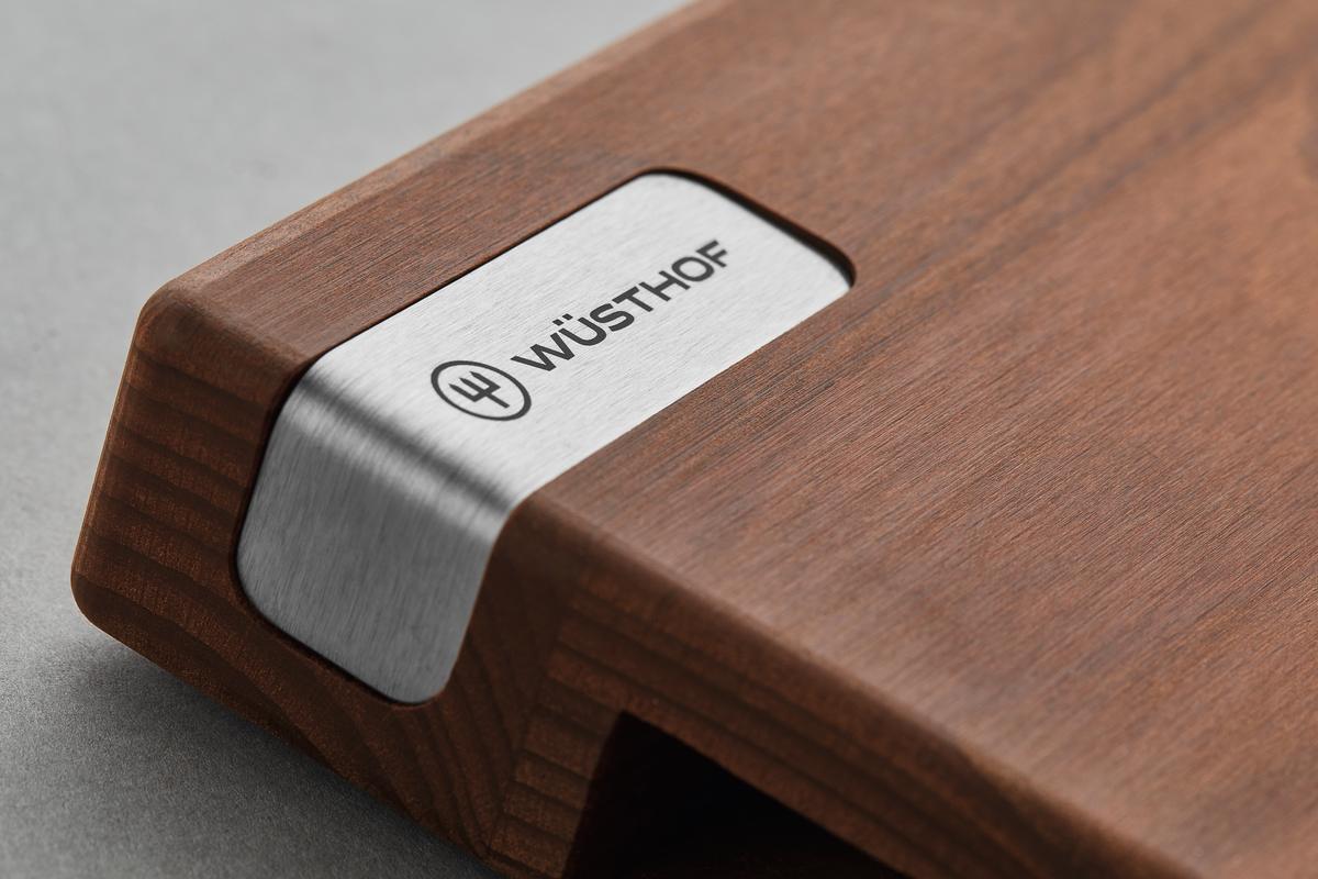 Heat-Treated Beech Cutting Board featuring a smooth wood surface with a stainless steel corner accent engraved with the WÜSTHOF logo for elegant kitchen use.