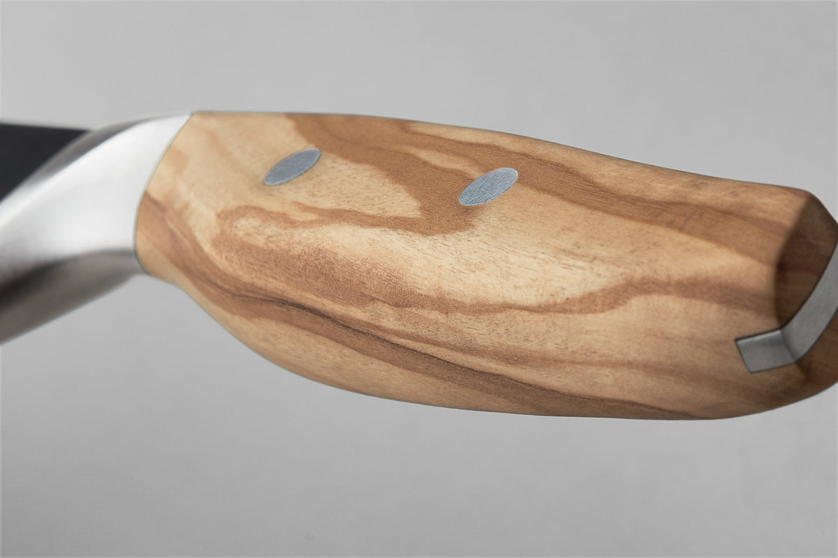 Close-up of the smooth olive wood handle with metal rivets on the Amici 5" Serrated Utility Knife, highlighting its ergonomic design and craftsmanship.