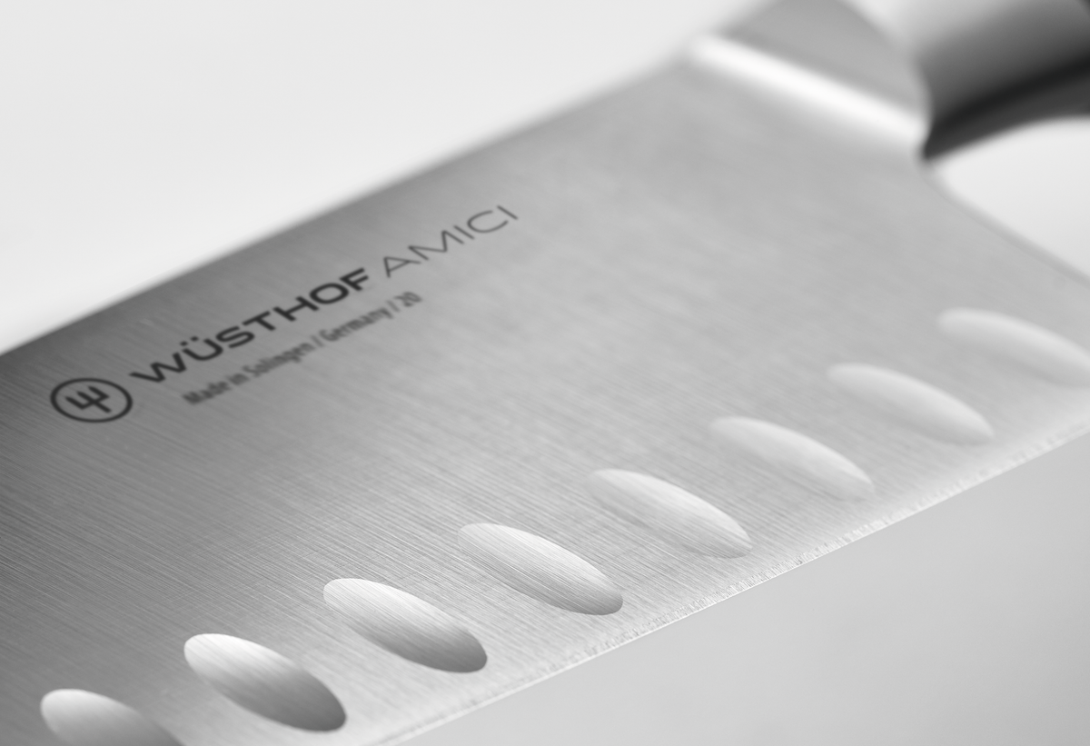 Amici 7" Hollow Edge Rotoku featuring a forged stainless steel blade with scalloped indentations and a polished smooth handle close-up.
