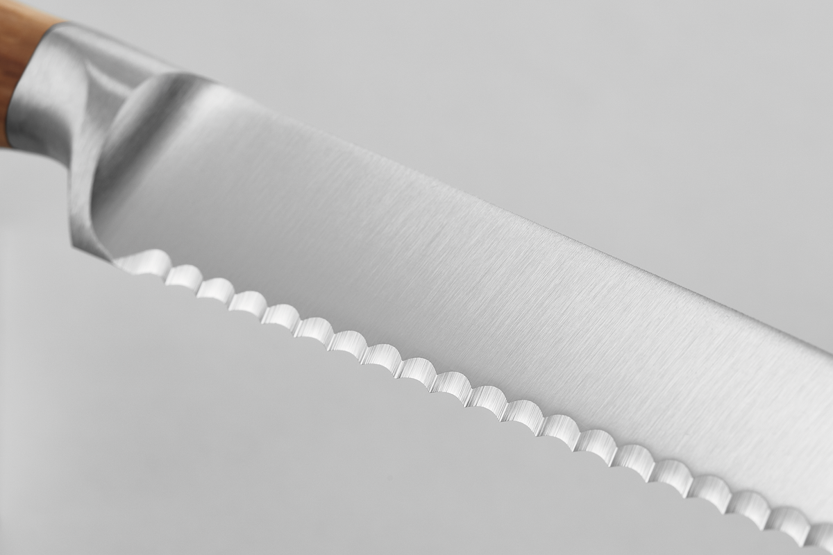Close-up of the finely serrated blade edge on the Amici 5" Serrated Utility Knife, showcasing sharp precision and stainless steel craftsmanship.